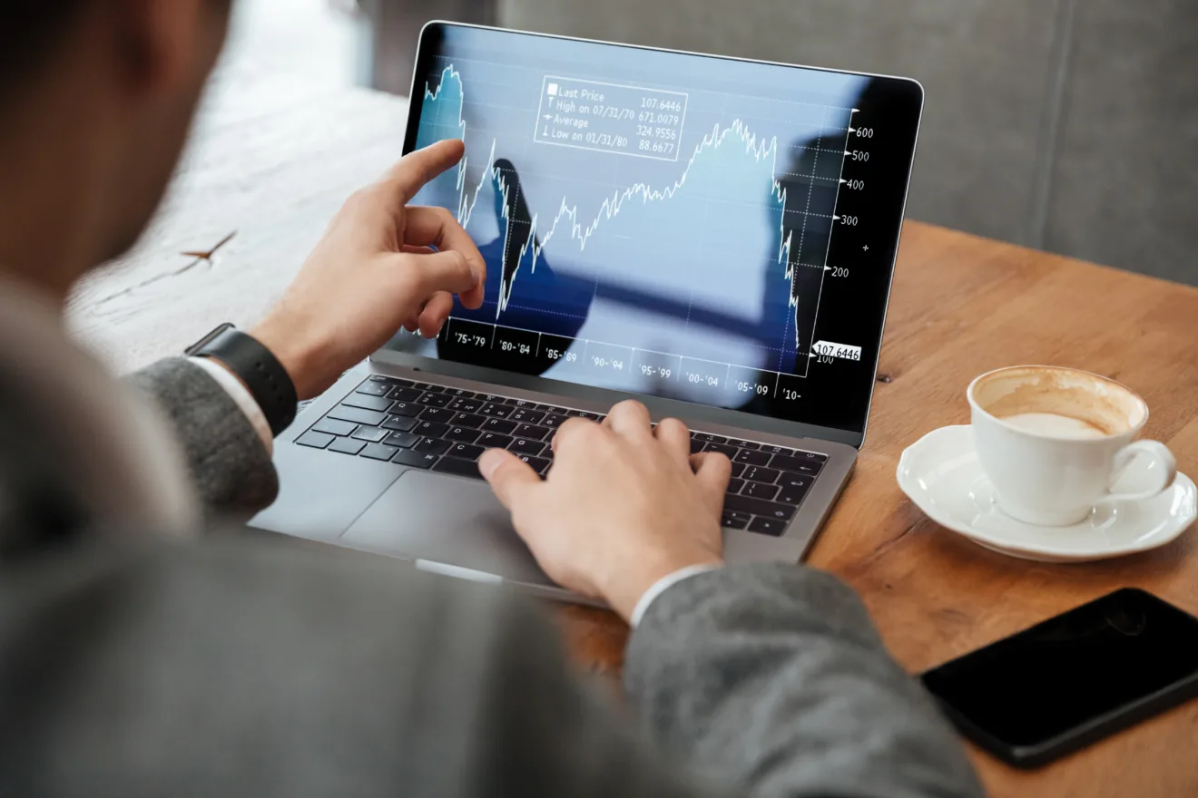 Cropped image of business man sitting by the table in cafe and analyzing indicators on laptop computer