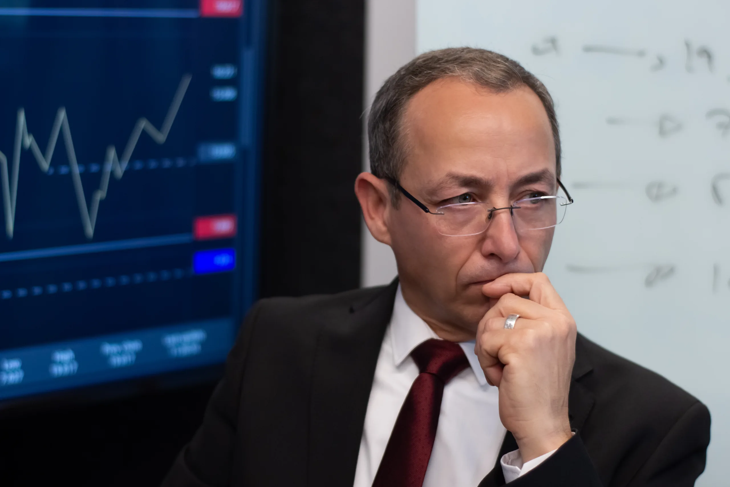 Portrait of experienced financial expert in office. Serious and thoughtful man working on his workplace analyzing financial data of stock market enjoying thinking. Financial analytics, business strategy concept