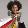 Jovem mulher negra com várias sacolas coloridas na mão/ ilustração de compras no dia do consumidor