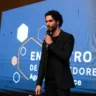 Na foto temos um homem de preto discursando na frente de um painel. O homem da foto é Felipe Muniz , co-fundador da HiSolver/ Foto usada como ilustração da matéria: HiSolver: conheça plataforma que usa IA para democratizar o aprendizado