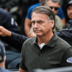 Foto de Bolsonaro, ex-presidente do Brasil, com uma roupa escura, em meio a vários seguranças.