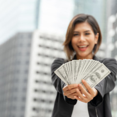 Successful beautiful Asian business  woman holding money US dollar bills in hand , business concept