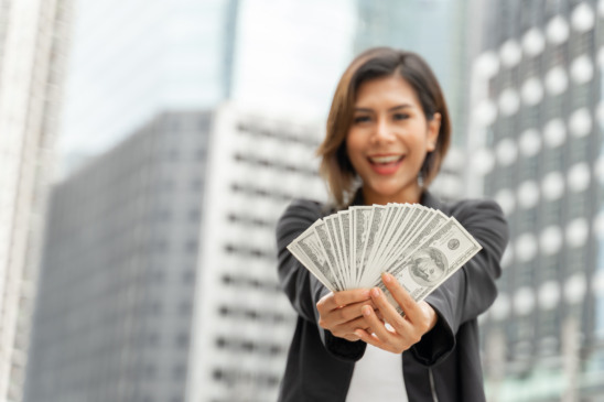 Successful beautiful Asian business  woman holding money US dollar bills in hand , business concept