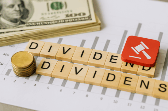 magem realista em alta resolução sobre taxação de dividendos, com elementos financeiros como pilhas de moedas douradas, cédulas de dinheiro, gráfico de barras e um ícone de martelo de juiz sobre uma planilha. A composição destaca o conceito de tributação sobre lucros distribuídos, ideal para conteúdos sobre economia, finanças, reforma tributária ou investimentos no Brasil.