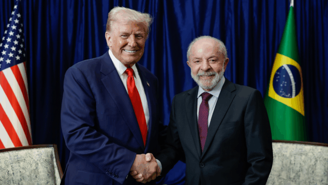 Presidente Lula e Trump de mãos dadas ao fundo as bandeiras de Brasil e EUA