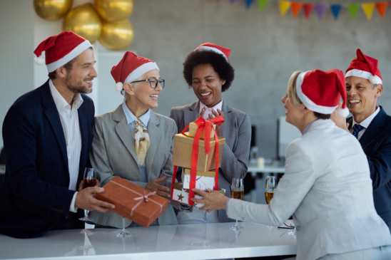 Happy mature businesswoman receiving Christmas present from her coworkers on office party.
